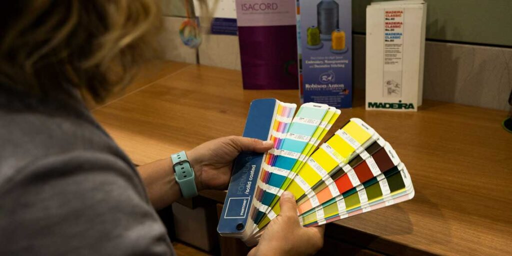 Woman holds up color block swatches with blues, yellows, reds, and greens