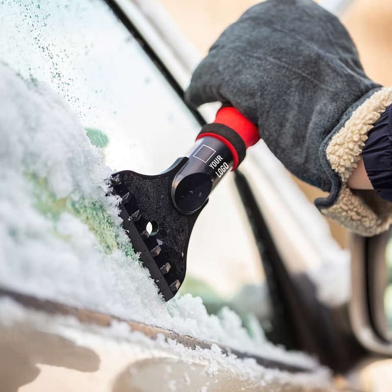 Person scraping a car window with a branded ice scraper.